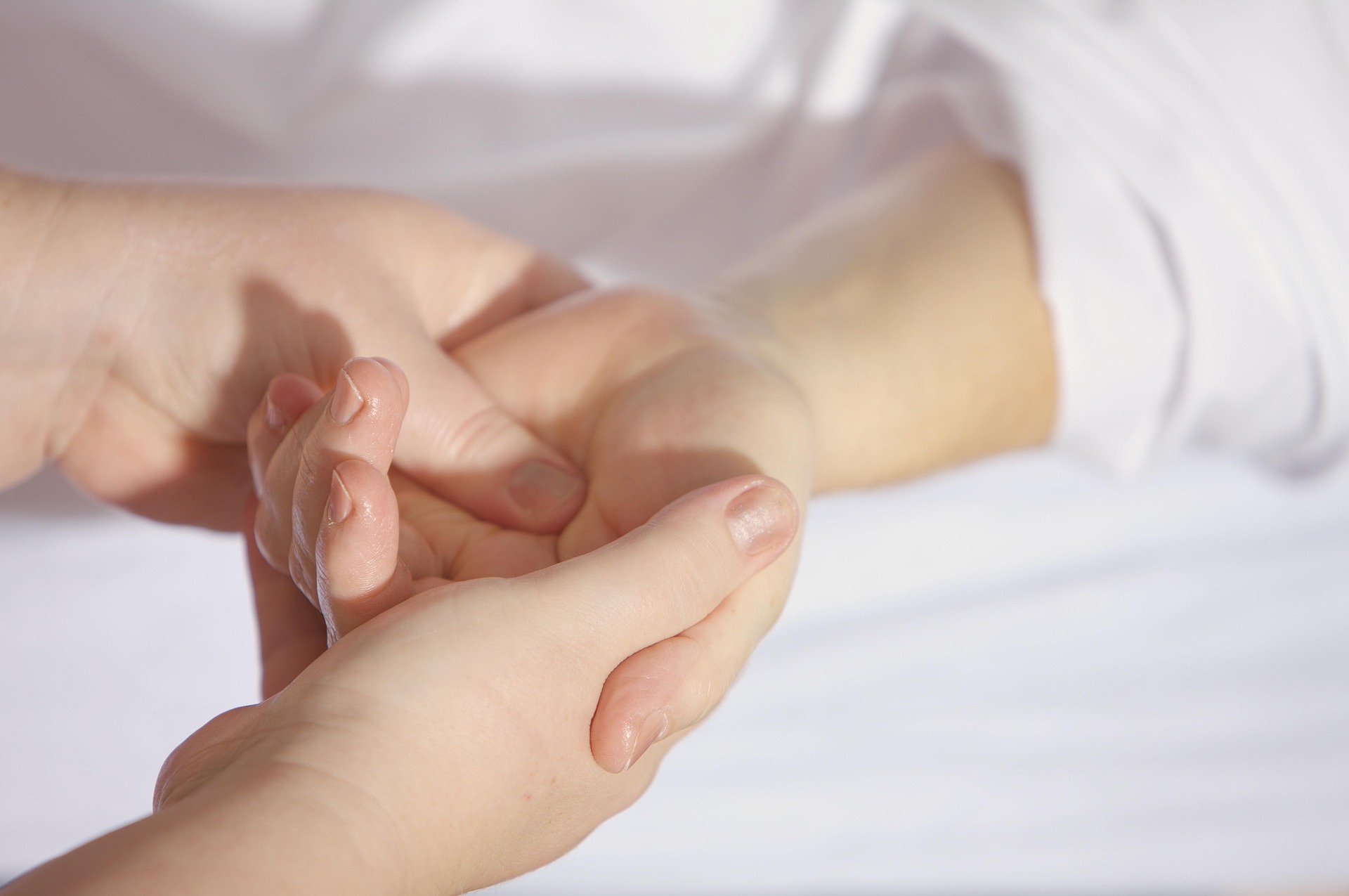A close-up of a person's hands providing a massage to the palm and thumb of another person's hand.